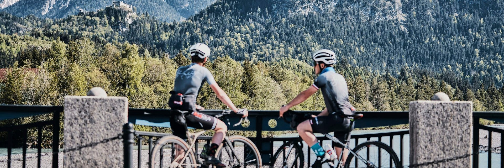 Hotel Bogner Hof **** © Dominik Somweber Zwei Radfahrer blickend auf schneebedeckten Berg und bewaldete Hügel