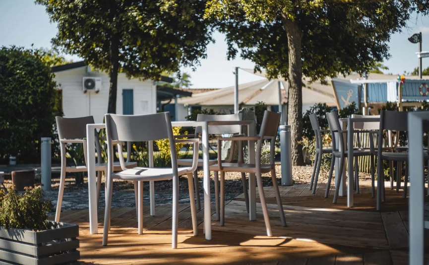 Empty chairs and tables in a sunny outdoor café seating area