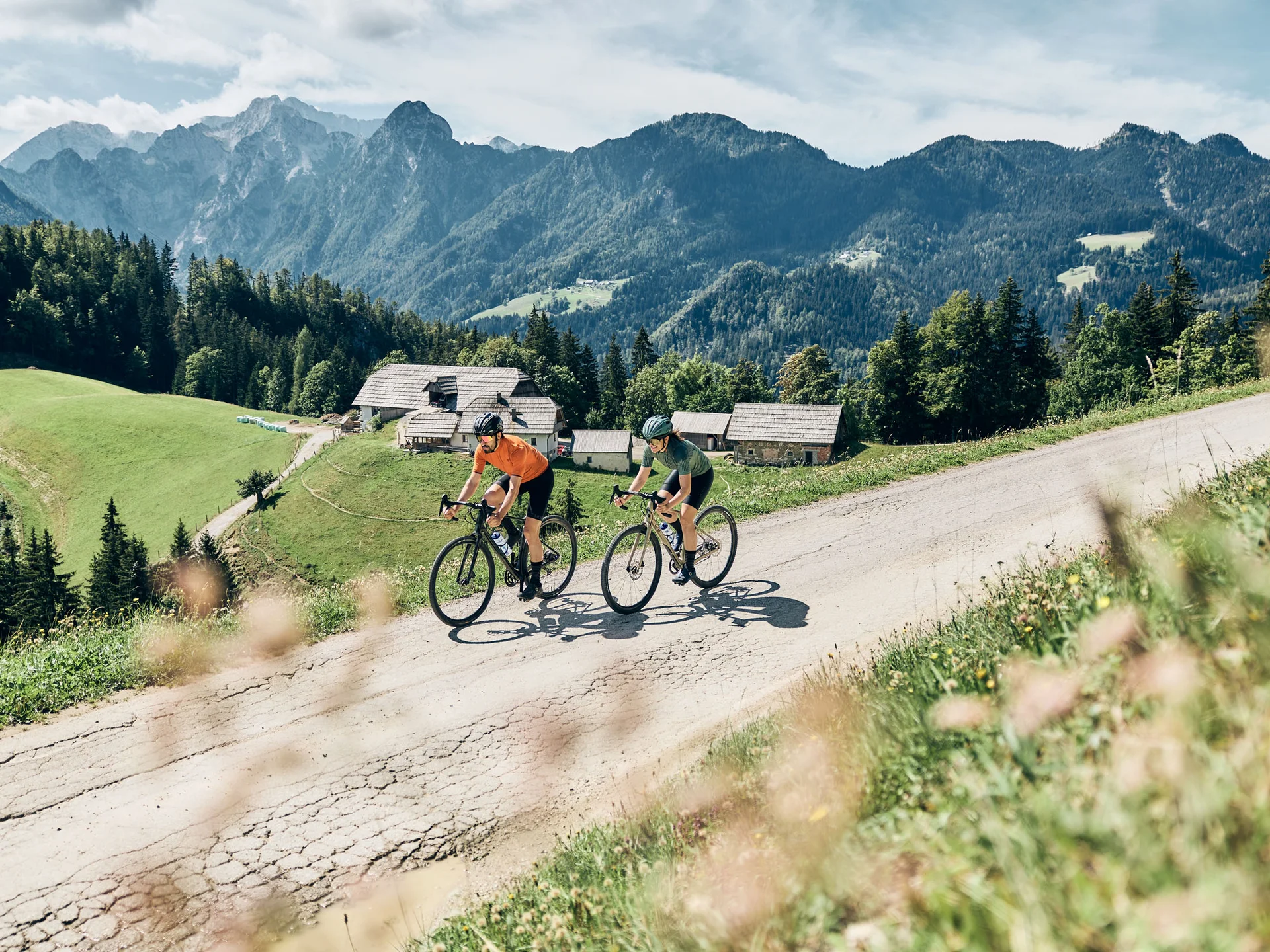 Zwei Radfahrer fahren bergauf auf einer Straße in den Bergen bei Sonnenschein