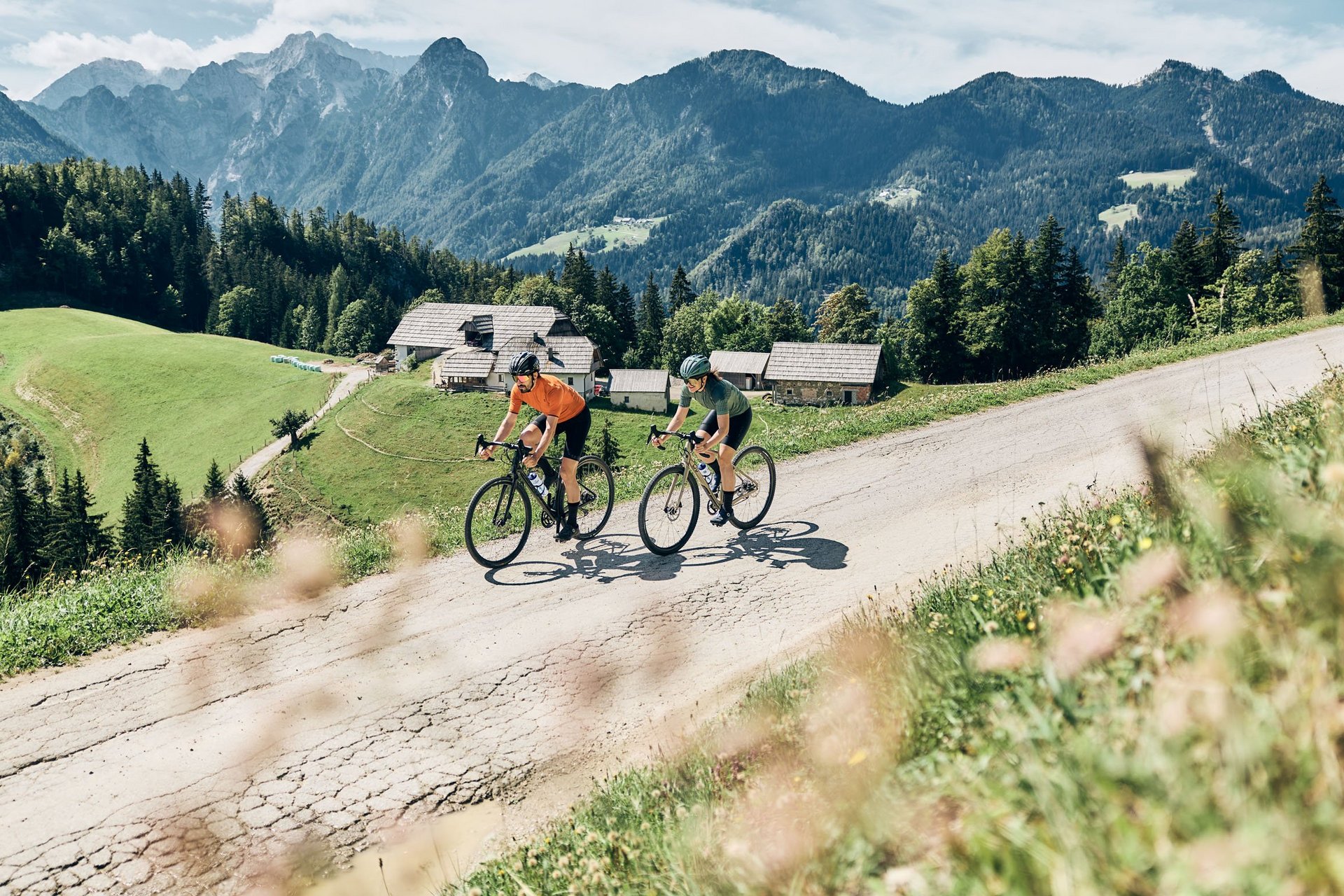 Zwei Radfahrer fahren bergauf auf einer Straße in den Bergen bei Sonnenschein