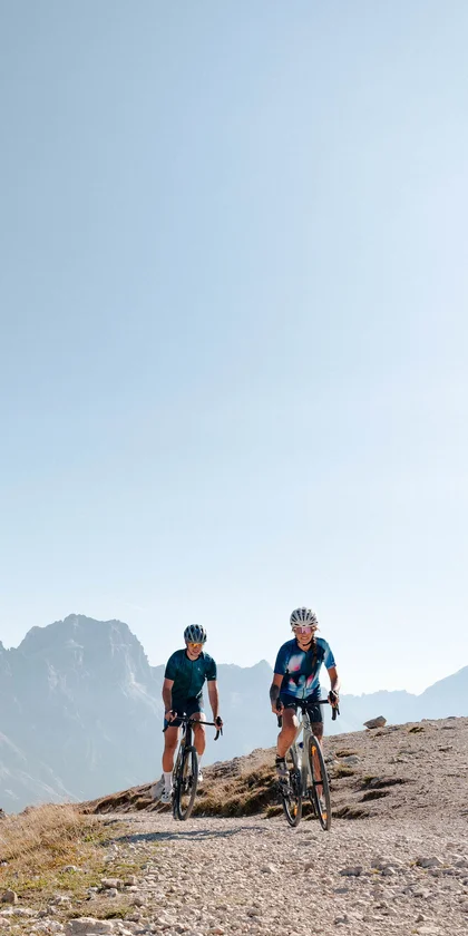 Zwei Radfahrer fahren auf einem Bergweg bei sonnigem Himmel