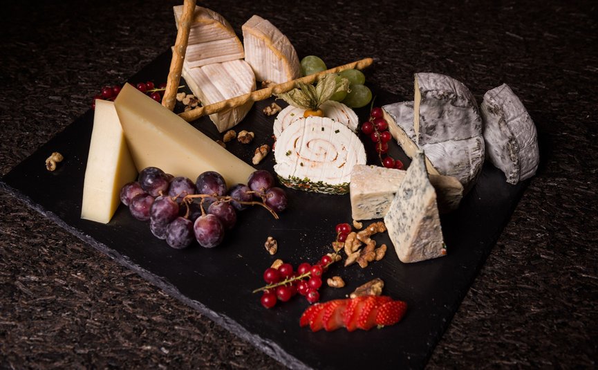 Verschiedene Käsesorten mit Trauben, Erdbeeren, roten Johannisbeeren und Walnüssen