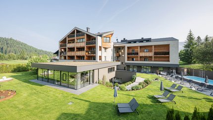 Modern hotel with garden, pool, and sun loungers in sunny setting