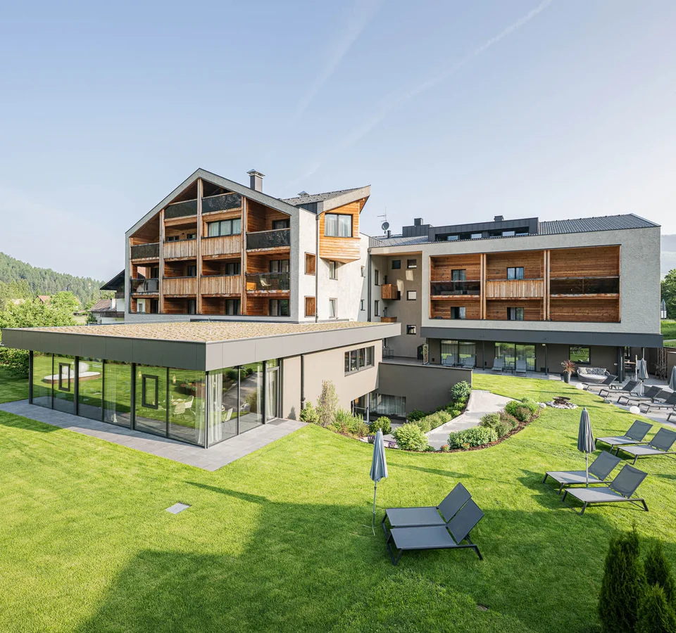 Basecamp mit Seele: Graveln im Hotel Laurin’s © Harald Wisthaler Modernes Hotel mit Garten, Pool und Sonnenliegen in sonniger Landschaft