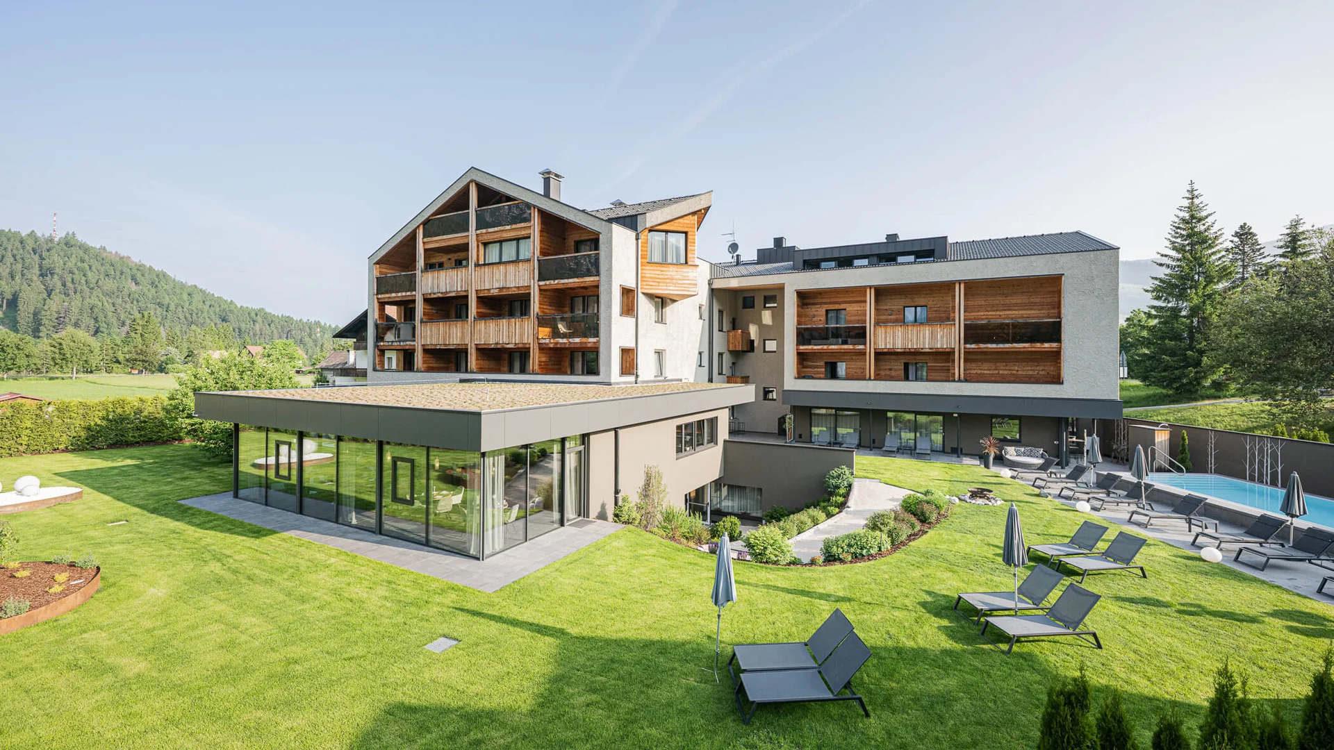 Epic Route Dolomites – 3 Zinnen – Gardasee © Harald Wisthaler Modernes Hotel mit Garten, Pool und Sonnenliegen in sonniger Landschaft