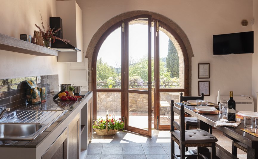 Helle Küche mit offenem Bogenfenster, Esstisch und Blick auf Terrasse und Garten