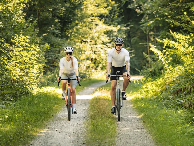 Gravelbiken im Bayerischen Wald © Stefan J. Wolf Photography Zwei Radfahrer in weißer Sportkleidung fahren auf einem Waldweg