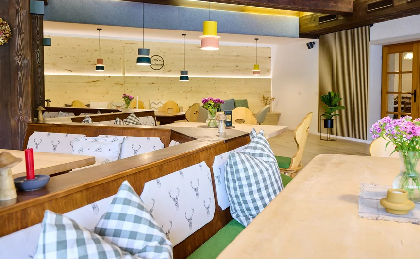 Cozy dining area with wooden tables, checkered pillows, and hanging lights