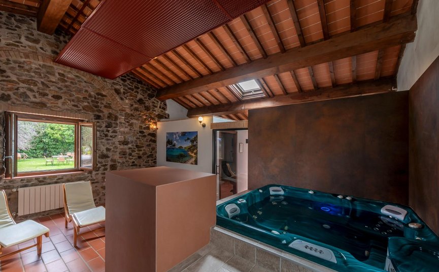 Innenraum mit Whirlpool, Holzdecke und gemütlichen Stühlen vor offnem Fenster