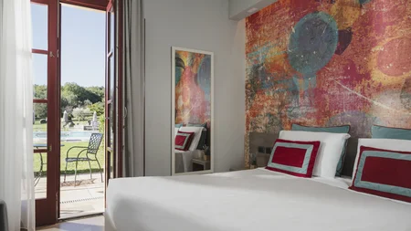 Gravelbiken in der Toskana © Hotel Casolare Le Terre Rosse Hell eingerichtetes Schlafzimmer mit Farbwand und Blick auf Terrasse und Pool