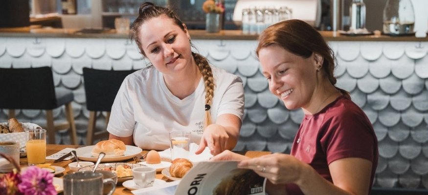 Zwei Frauen beim Frühstück und Lesen in einem Magazin im Café