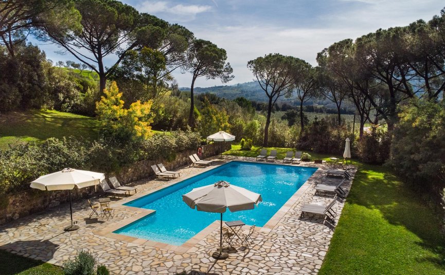 Außenpool mit Liegestühlen und Sonnenschirmen in grüner Landschaft