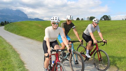 Schwoich round © Michael Küchl Three cyclists riding on a path with green fields and mountains in background