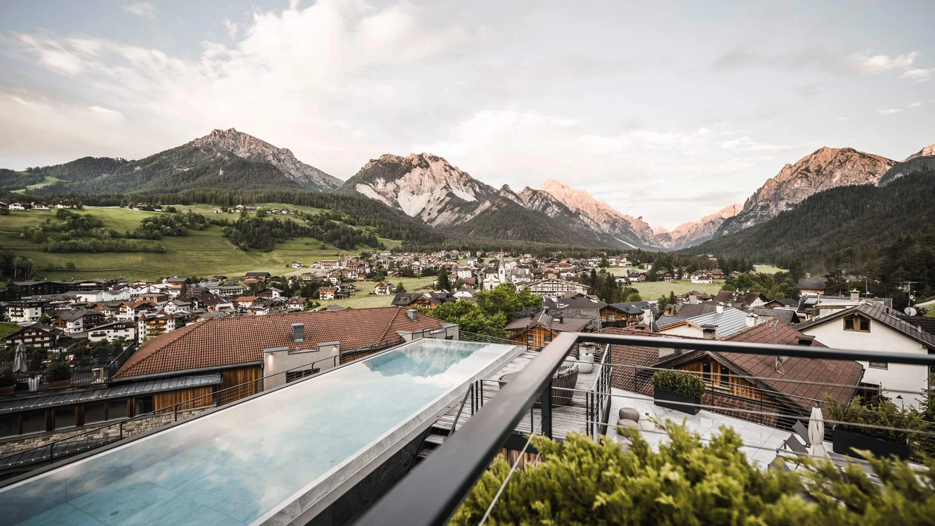 Blick auf ein Dorf in den Alpen mit einem Pool im Vordergrund
