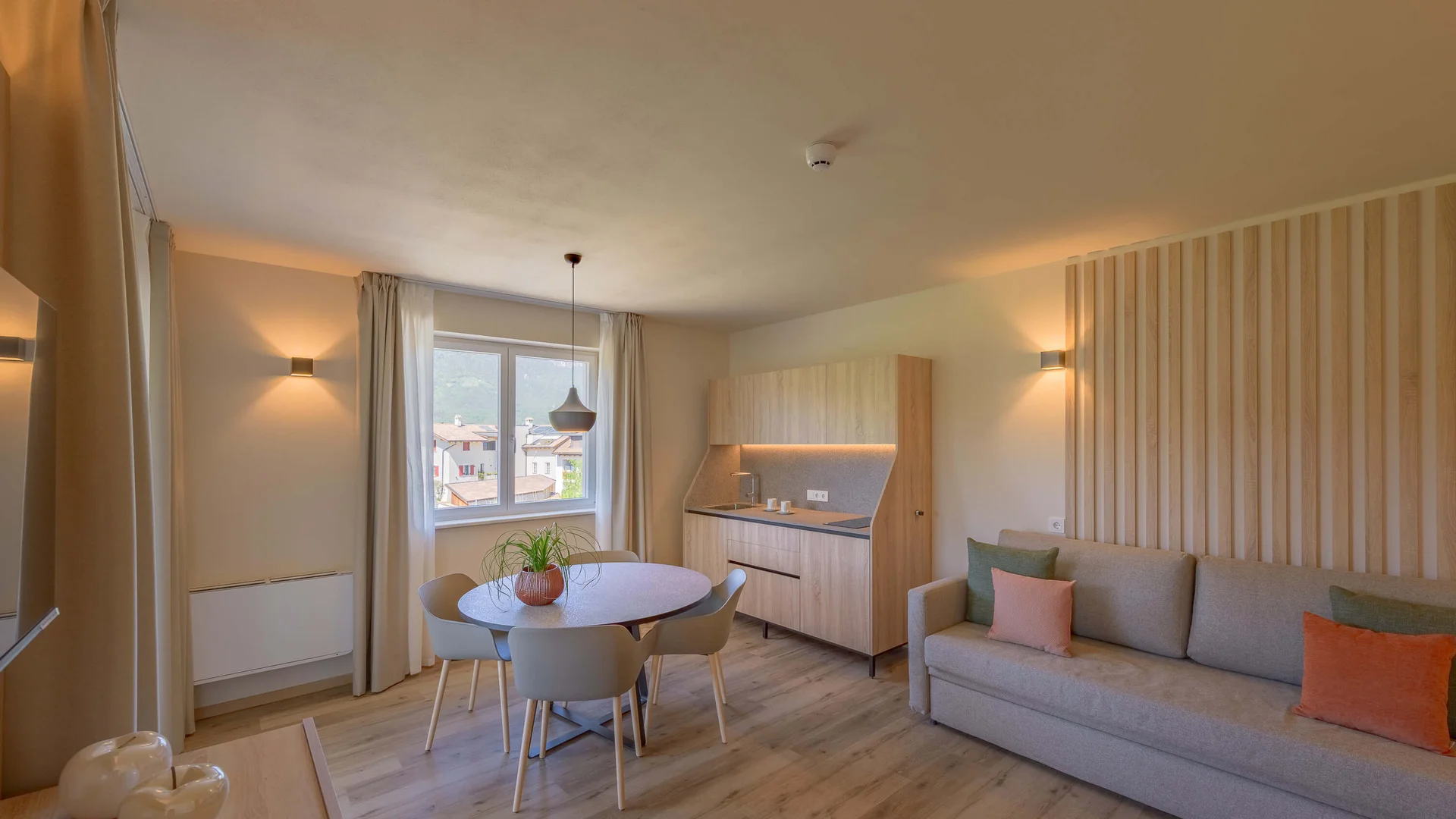 Gemütliches Wohnzimmer mit Esstisch, Küchenzeile und Sofa mit bunten Kissen