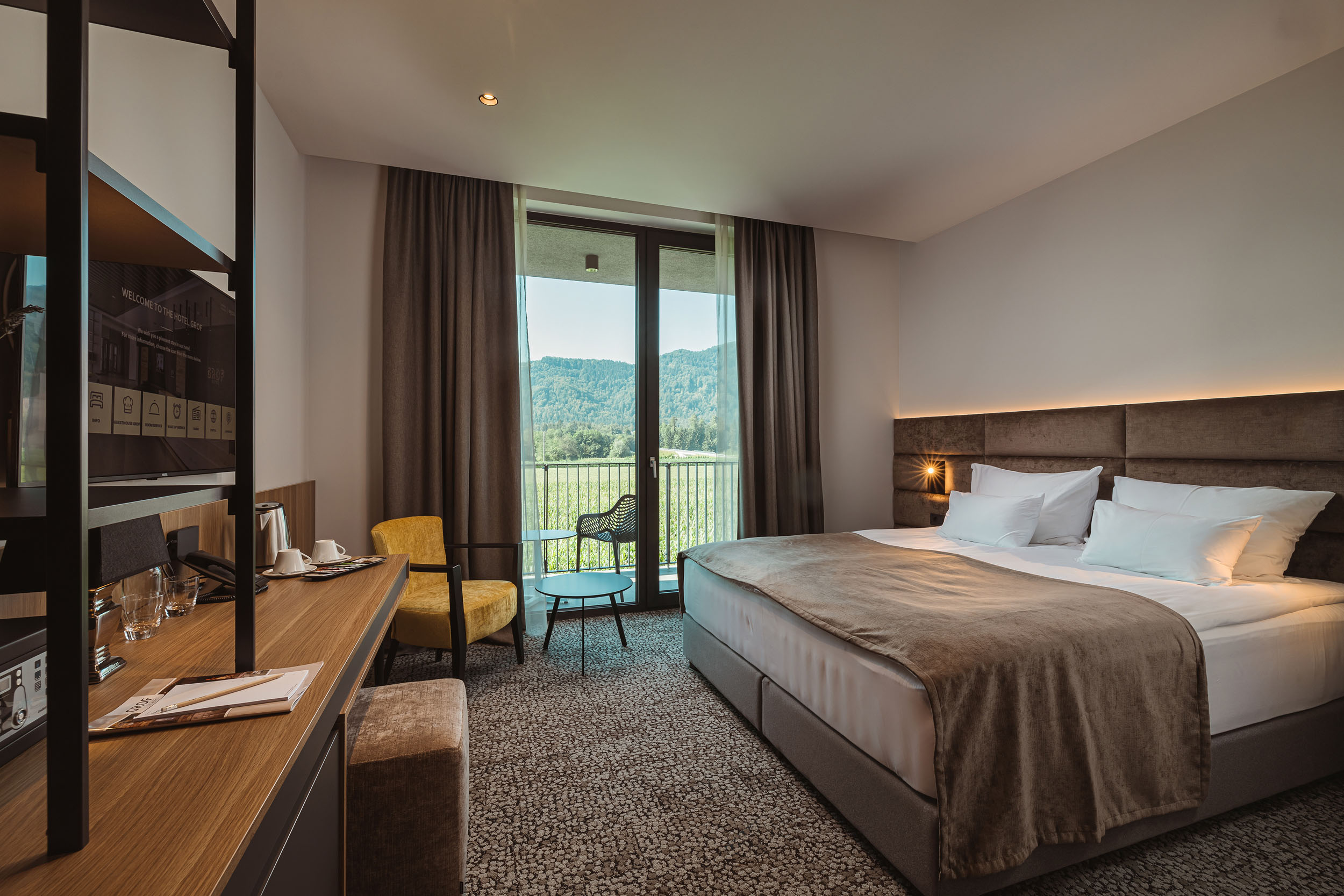 Slovenia Gravel Experience © Ziga Intihar Modern hotel room with double bed, desk, and balcony overlooking mountains